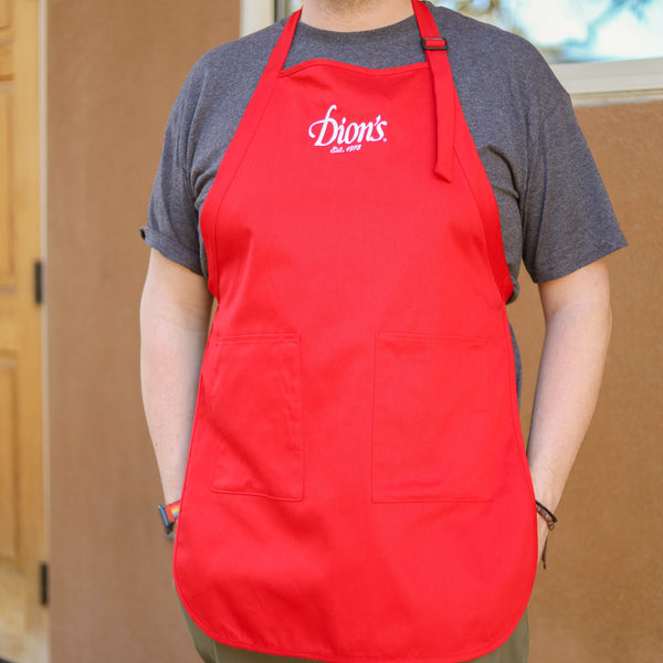 A pizza artist donning a Dion's Fan Shop apron stands outside designing pizza kits.
