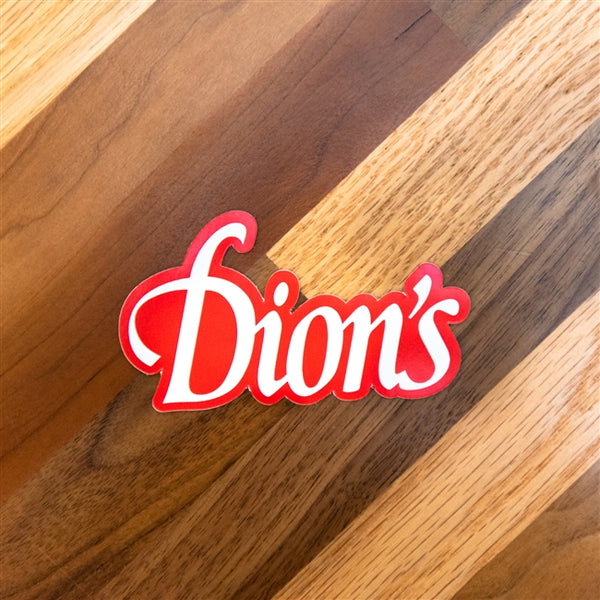 Dion's Fan Shop logo on a wooden table with a Dion's Sticker decal.