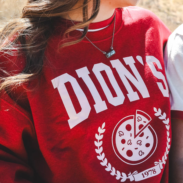 Dion's Fan Shop Collegiate Crewneck: red sweatshirt with “DION’S” in white, a pizza slice and laurel graphic, plus “1978” below—campus-perfect apparel for fans of this legendary pizza brand.