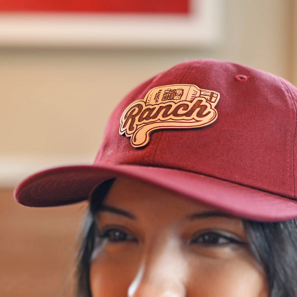 A close-up shows someone wearing a Dion's Fan Shop Ranch Cap adorned with the iconic "Ranch" logo and sauce bottle graphic, adding a hint of swag to their style.