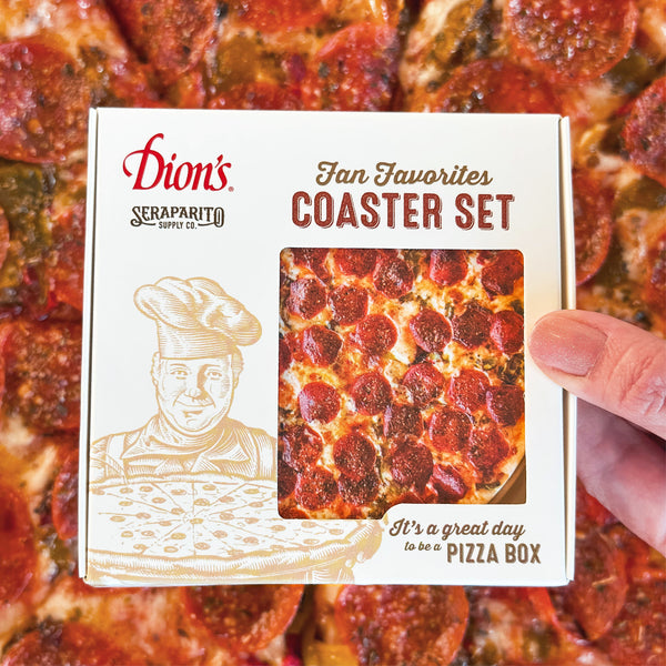 A hand holds a Dion's x Seraparito Fan Favorites Coaster Set box from Dion's Fan Shop, designed like a pizza—an absorbent coaster collection that's the perfect cheesy gift, with real pizza in the background.
